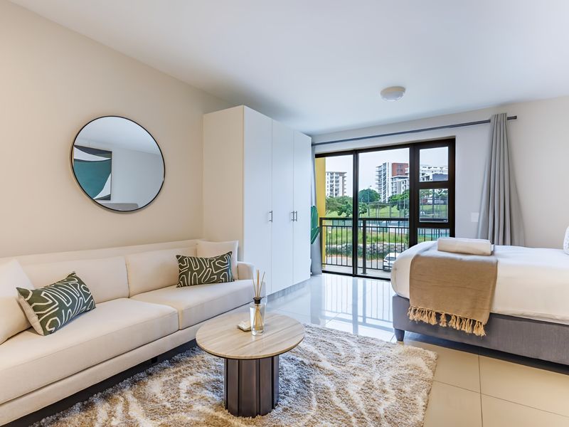 A modern, well-lit bedroom featuring built-in wardrobes, tiled flooring, and direct access to a private balcony with exterior views.