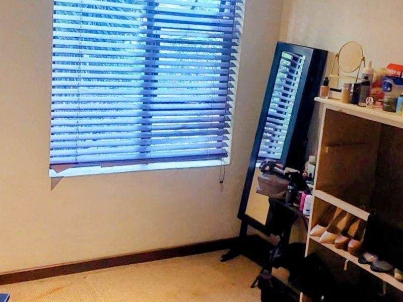 A bedroom featuring carpeted flooring and venetian blinds, providing a functional space with neutral wall finishes.