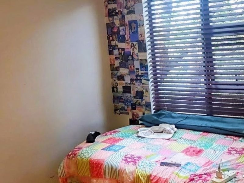 A bedroom featuring a window with venetian blinds, providing natural light and a view of the exterior.
