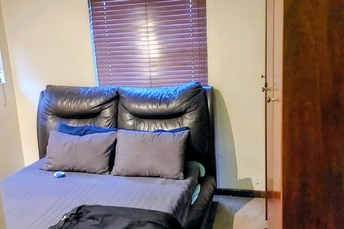 A bedroom featuring a built-in wardrobe and venetian blinds, providing a functional space with standard finishes.