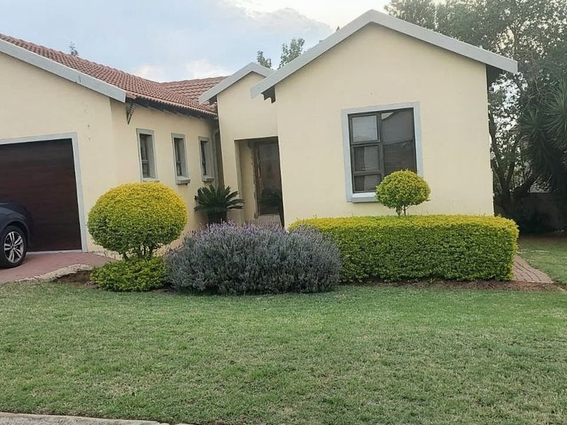 Front elevation of a single-story residential house featuring a double garage, paved driveway, and well-maintained front garden.