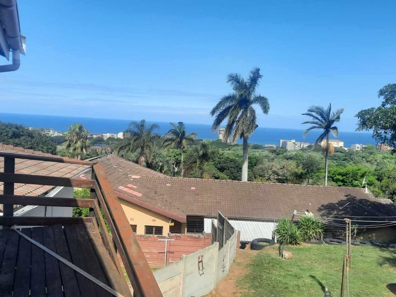 Elevated view from a wooden deck overlooking the surrounding neighbourhood with a scenic ocean horizon in the distance.