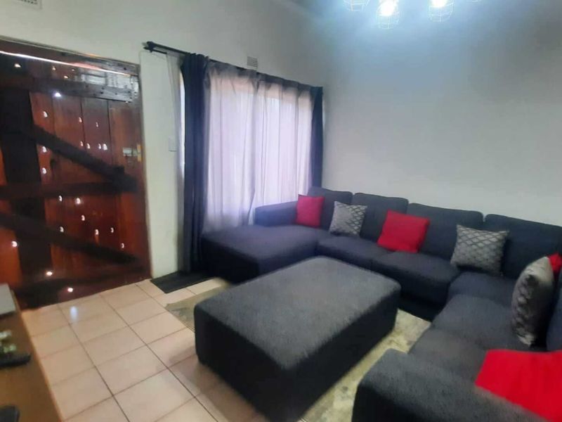 A living room featuring tiled flooring and a distinctive wooden stable-style entrance door, providing a functional and cozy living space.