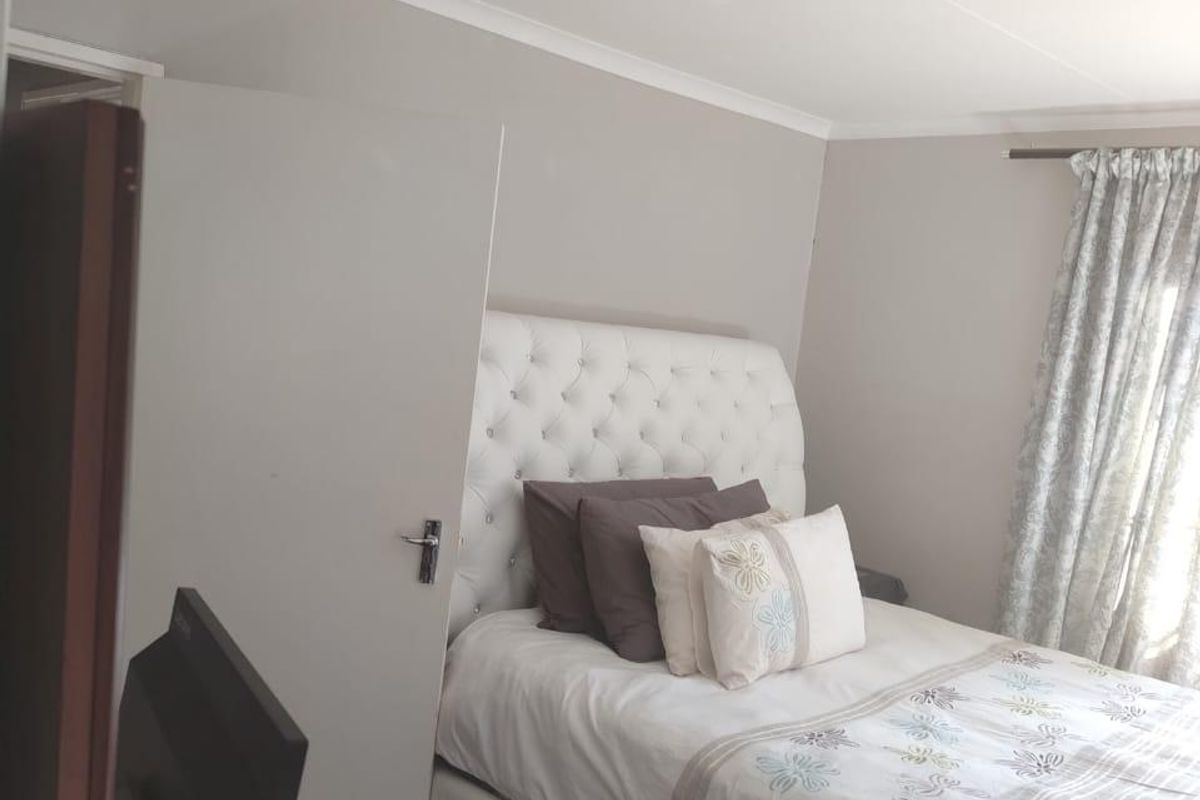 A bedroom featuring neutral wall tones, cove cornicing, and a window fitted with a curtain rod.