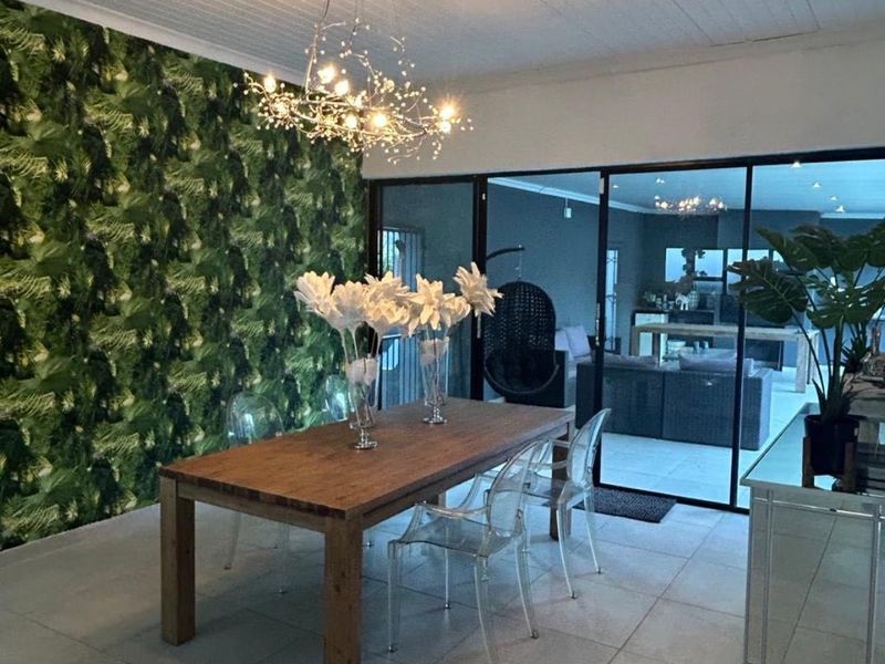 A dining area featuring tiled flooring, a tongue and groove ceiling, and large sliding glass doors that provide a view into the adjacent living space.