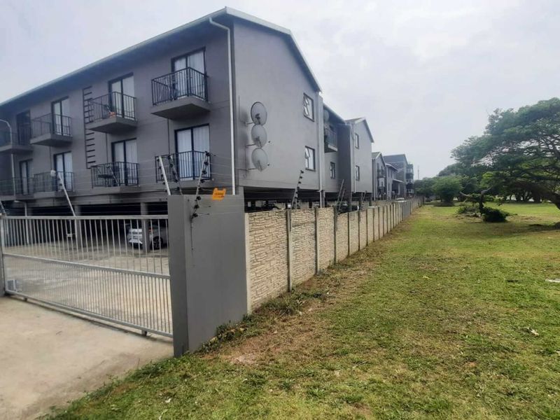 Exterior view of a multi-story apartment complex featuring secure gated access, electric fencing, and private balconies.