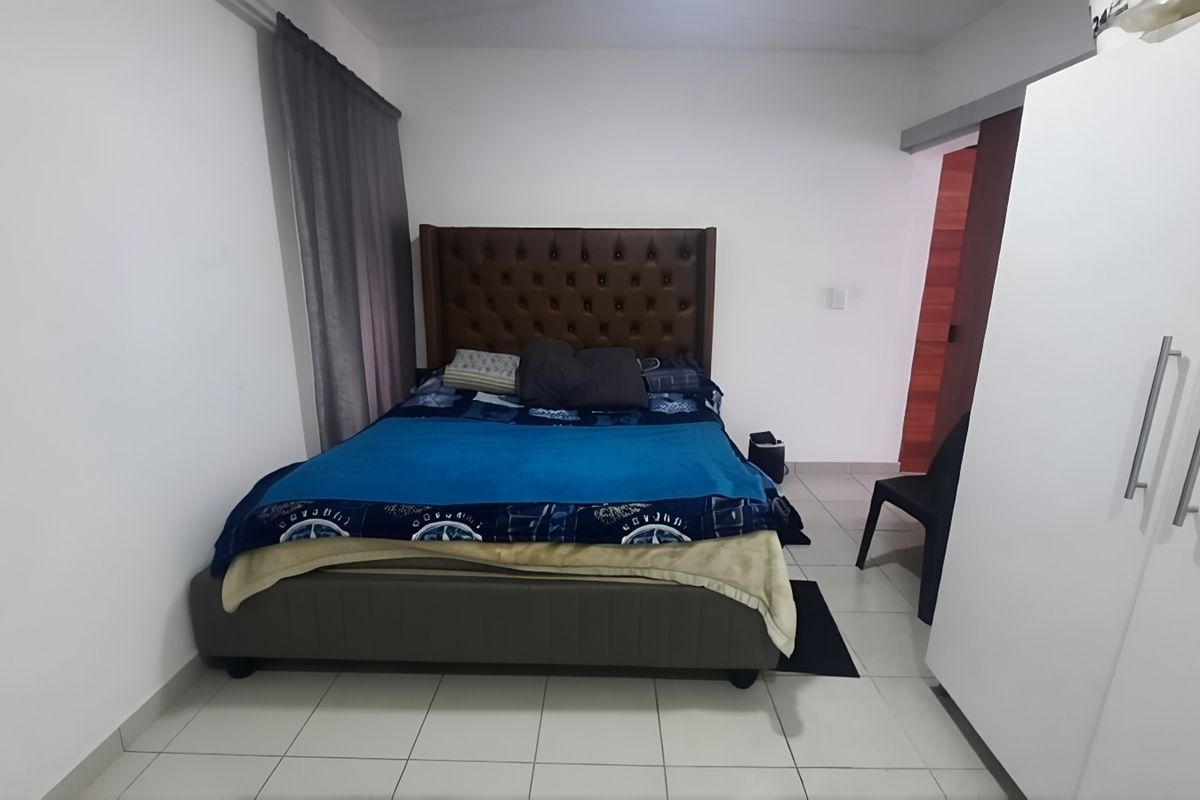 A functional bedroom featuring tiled flooring, a built-in wardrobe, and a sliding door entrance.
