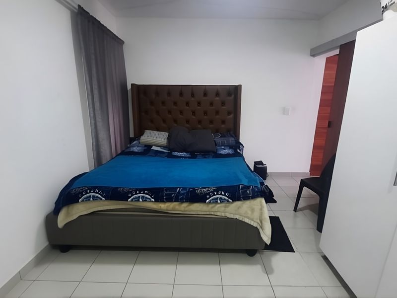 A functional bedroom featuring tiled flooring, a built-in wardrobe, and a sliding door entrance.