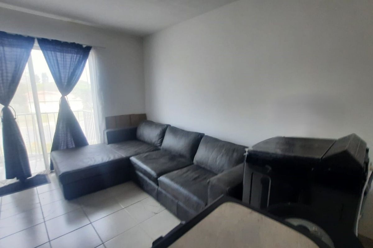 A living room area featuring tiled flooring and a sliding glass door providing access to an outdoor space.