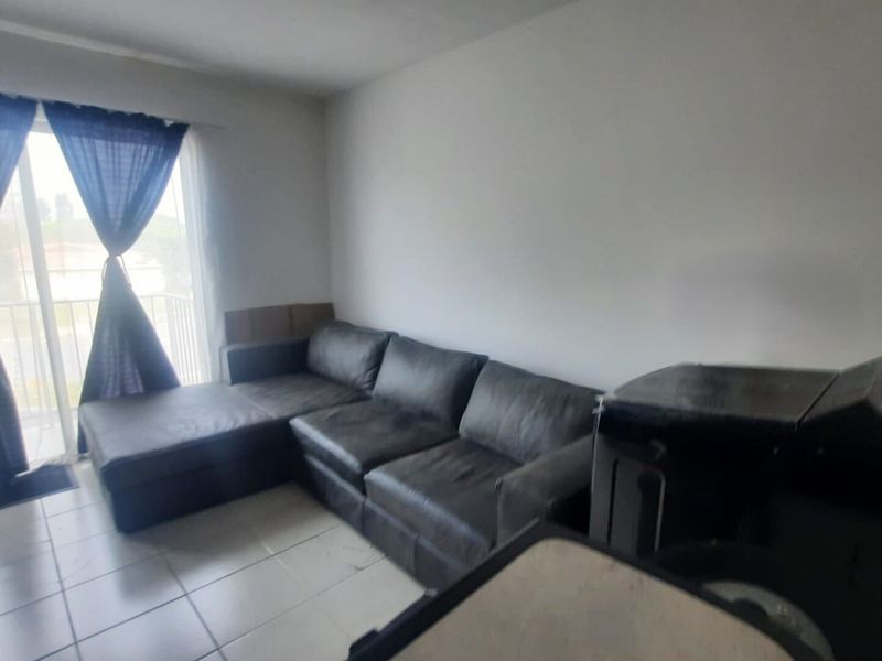 A living room area featuring tiled flooring and a sliding glass door providing access to an outdoor space.