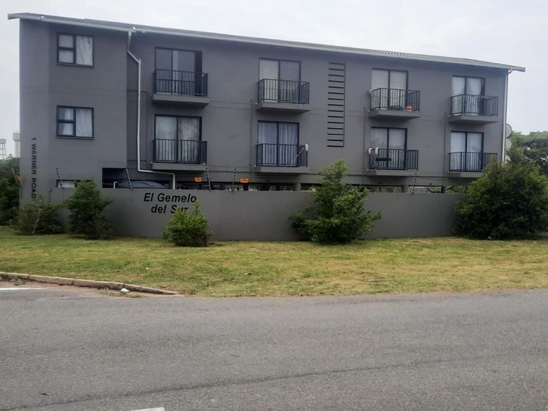 Exterior view of the El Gemelo del Sur apartment complex, featuring a multi-story building with private balconies and secure perimeter walling.