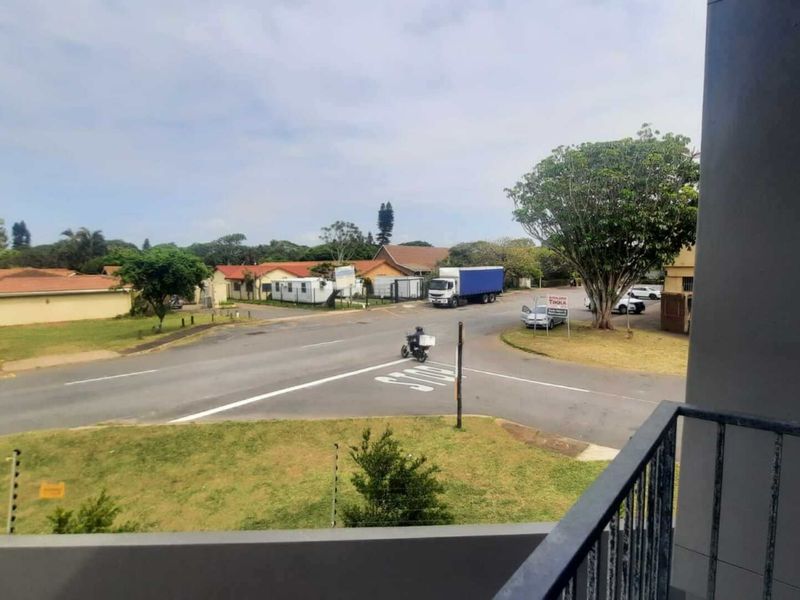 An elevated view from a balcony overlooking a suburban street intersection and surrounding residential neighborhood.