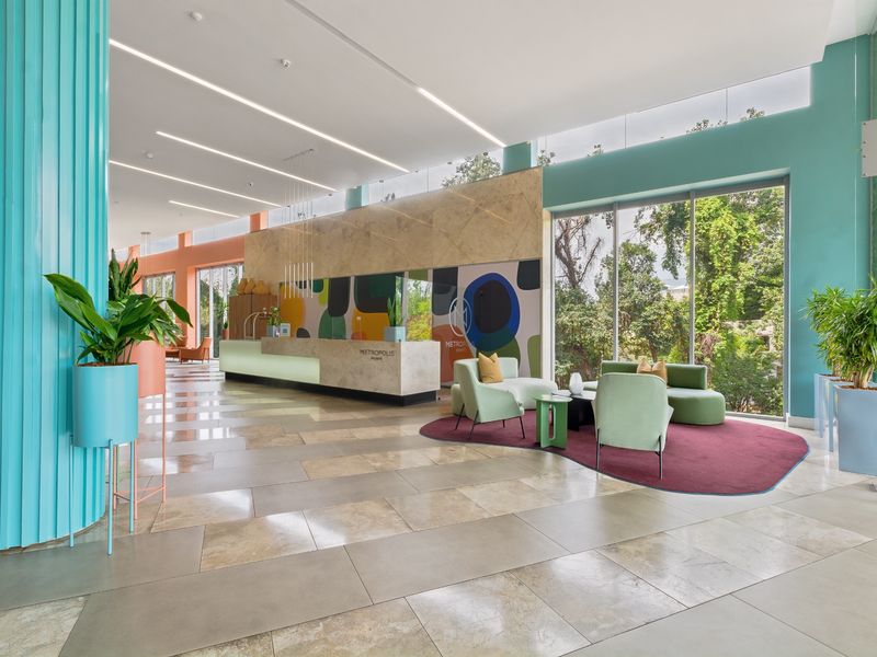 Modern, spacious apartment building lobby featuring a stone reception desk, large floor-to-ceiling windows, and contemporary interior finishes.