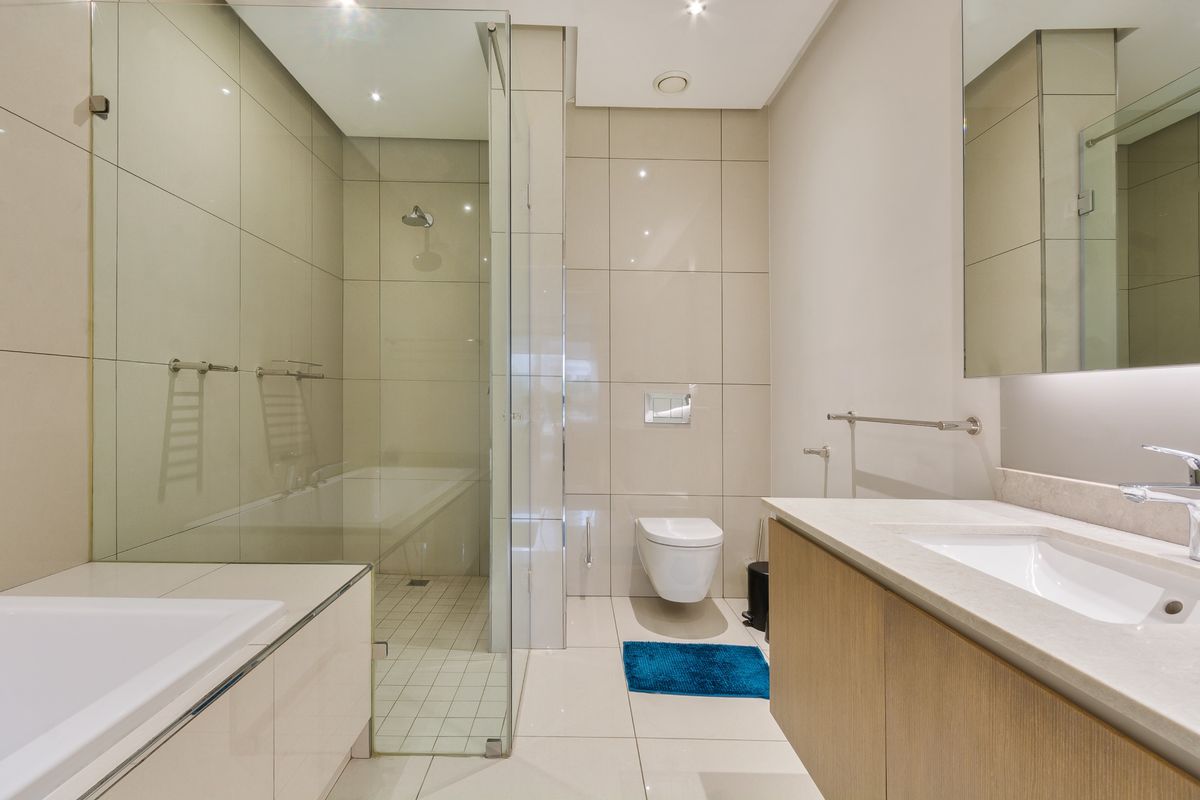 Modern bathroom featuring a wall-hung toilet, glass-enclosed shower, and a sleek vanity with integrated basin and mirror.