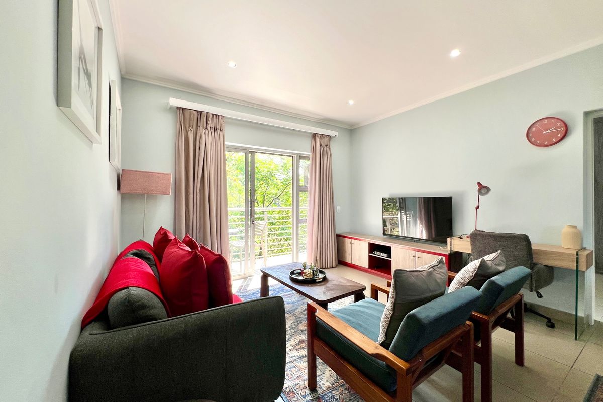 A bright and well-maintained living room featuring tiled flooring, recessed lighting, and a sliding glass door leading to a balcony.