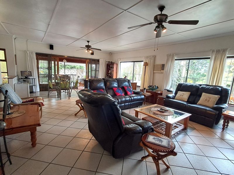 Spacious open-plan living area featuring tiled flooring, ceiling fans, and large sliding doors providing access to the outdoor patio space.