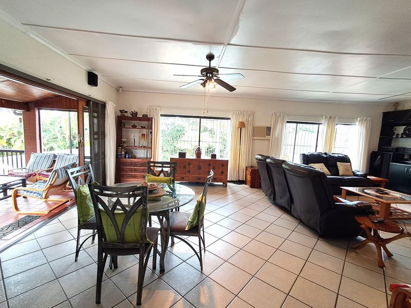 Spacious open-plan living and dining area featuring tiled flooring, a ceiling fan, and large sliding doors providing seamless access to the outdoor patio.