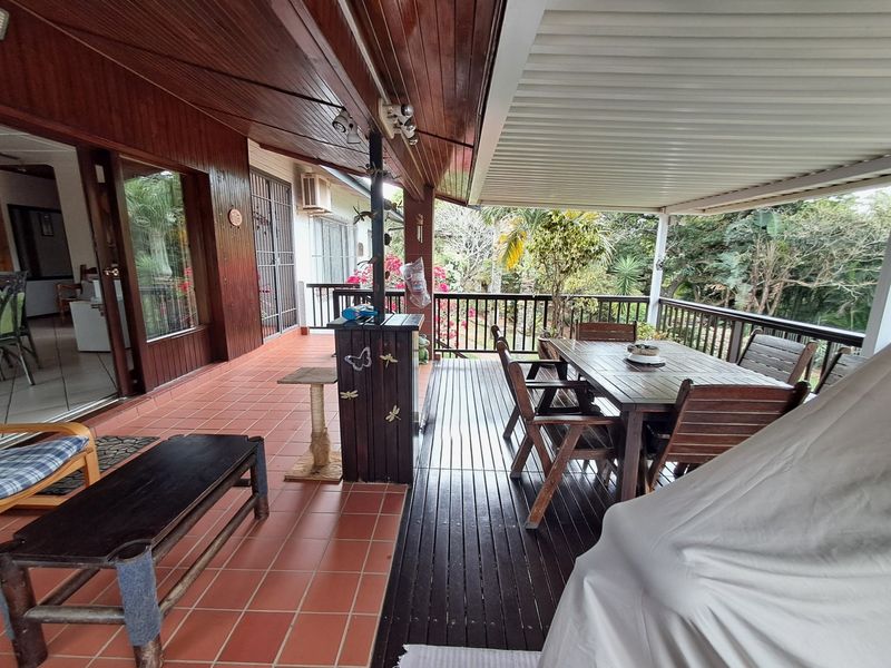 Spacious covered patio featuring a combination of timber decking and tiled flooring, providing an ideal outdoor entertainment area overlooking the garden.
