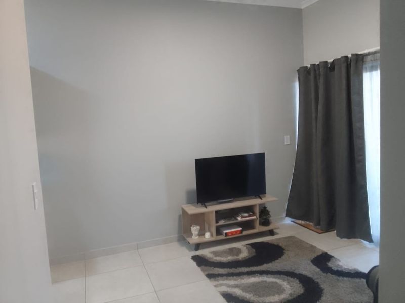 A living room area featuring neutral wall paint, tiled flooring, and a sliding glass door providing access to the exterior.