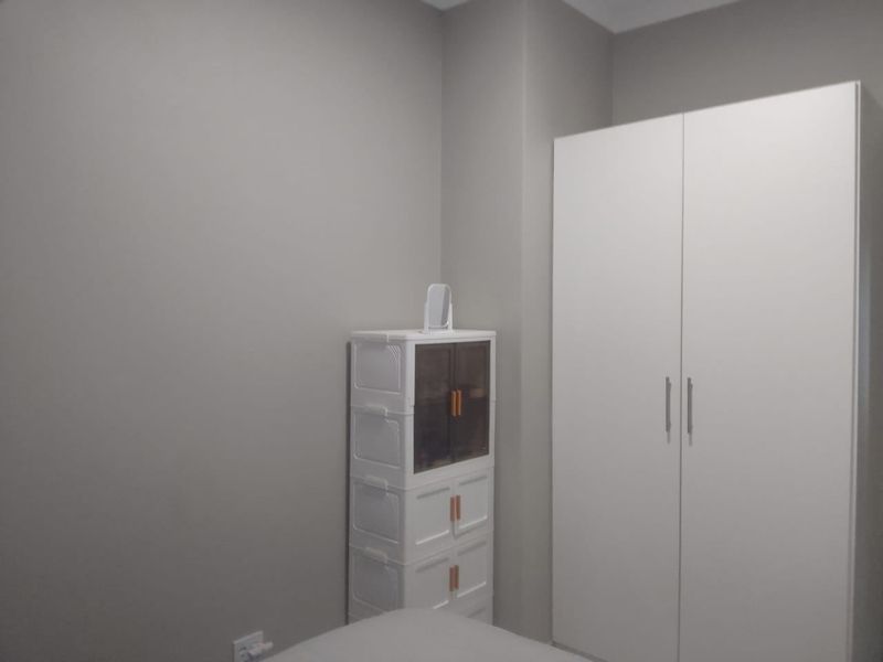 A clean bedroom featuring a neutral color palette and a functional built-in wardrobe, offering a simple and tidy living space.