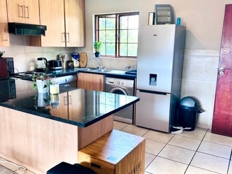 A functional kitchen featuring granite countertops, laminate cabinetry, tiled flooring, and a tiled backsplash, providing a practical layout for daily use.