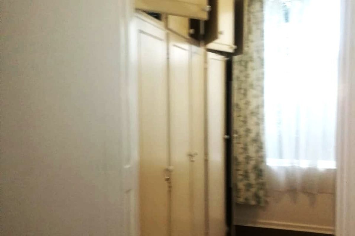 A narrow hallway featuring extensive built-in floor-to-ceiling cupboards and overhead storage units, providing ample storage space.