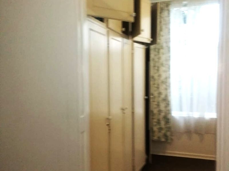 A narrow hallway featuring extensive built-in floor-to-ceiling cupboards and overhead storage units, providing ample storage space.