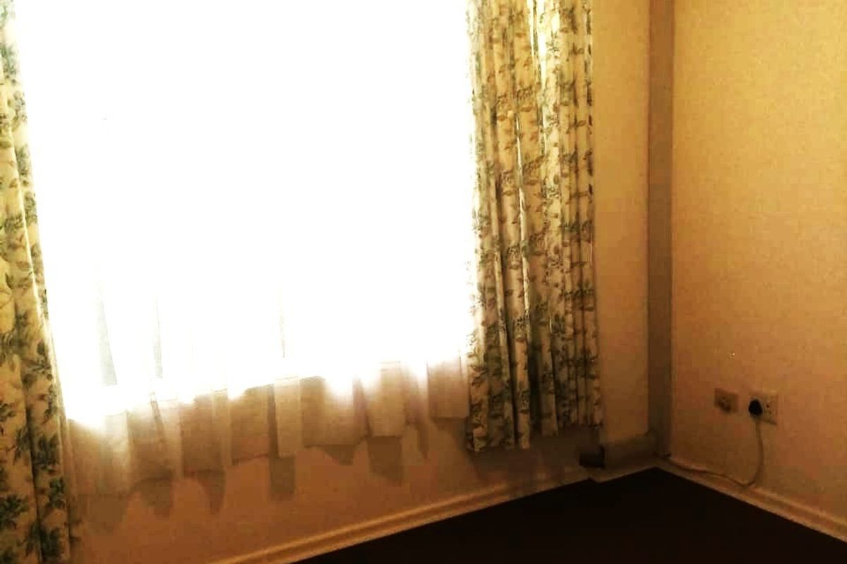 An empty bedroom featuring carpet flooring and a wall-mounted split-system air conditioner.