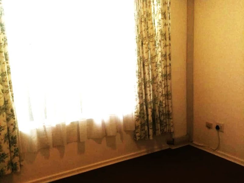 An empty bedroom featuring carpet flooring and a wall-mounted split-system air conditioner.