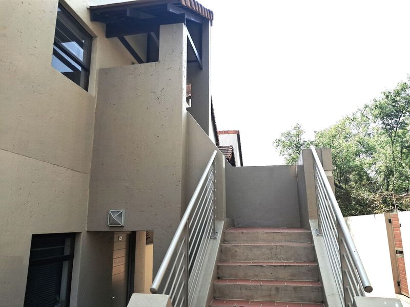 Exterior view of an apartment entrance featuring a staircase with metal handrails and tiled steps leading to the front door.