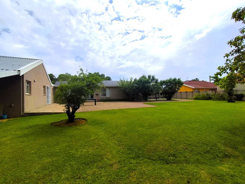 Spacious rear garden featuring a large lawn area and a paved patio adjacent to the house structure.
