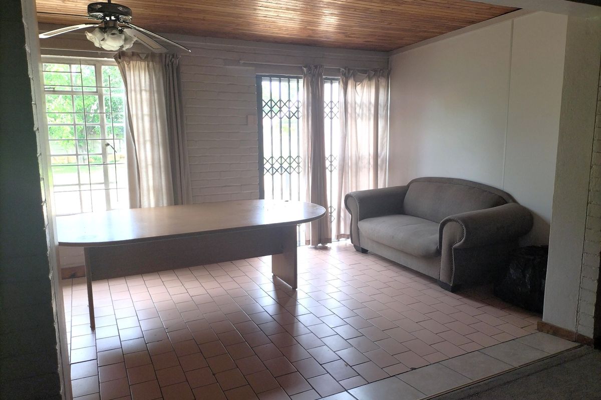 Spacious living area featuring a timber ceiling, ceiling fan, and tiled flooring, with direct access to the exterior through security-gated doors.