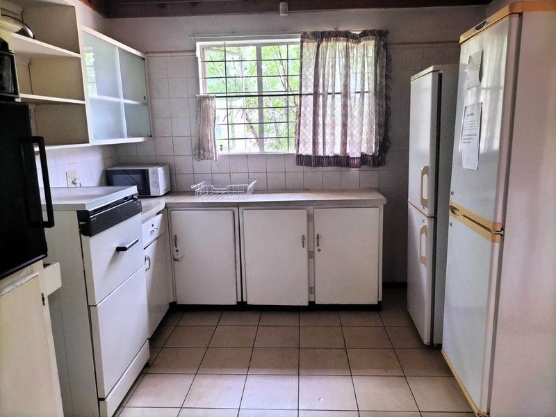 A functional kitchen featuring tiled flooring, built-in cabinetry, and a tiled backsplash, offering a dated aesthetic ready for modernization.