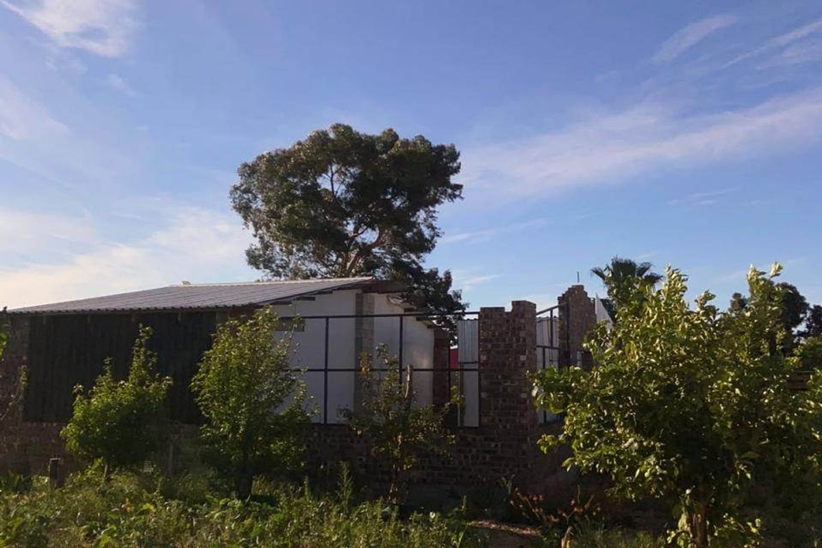View of a residential property under construction featuring exposed brickwork and metal roofing set within a garden area.