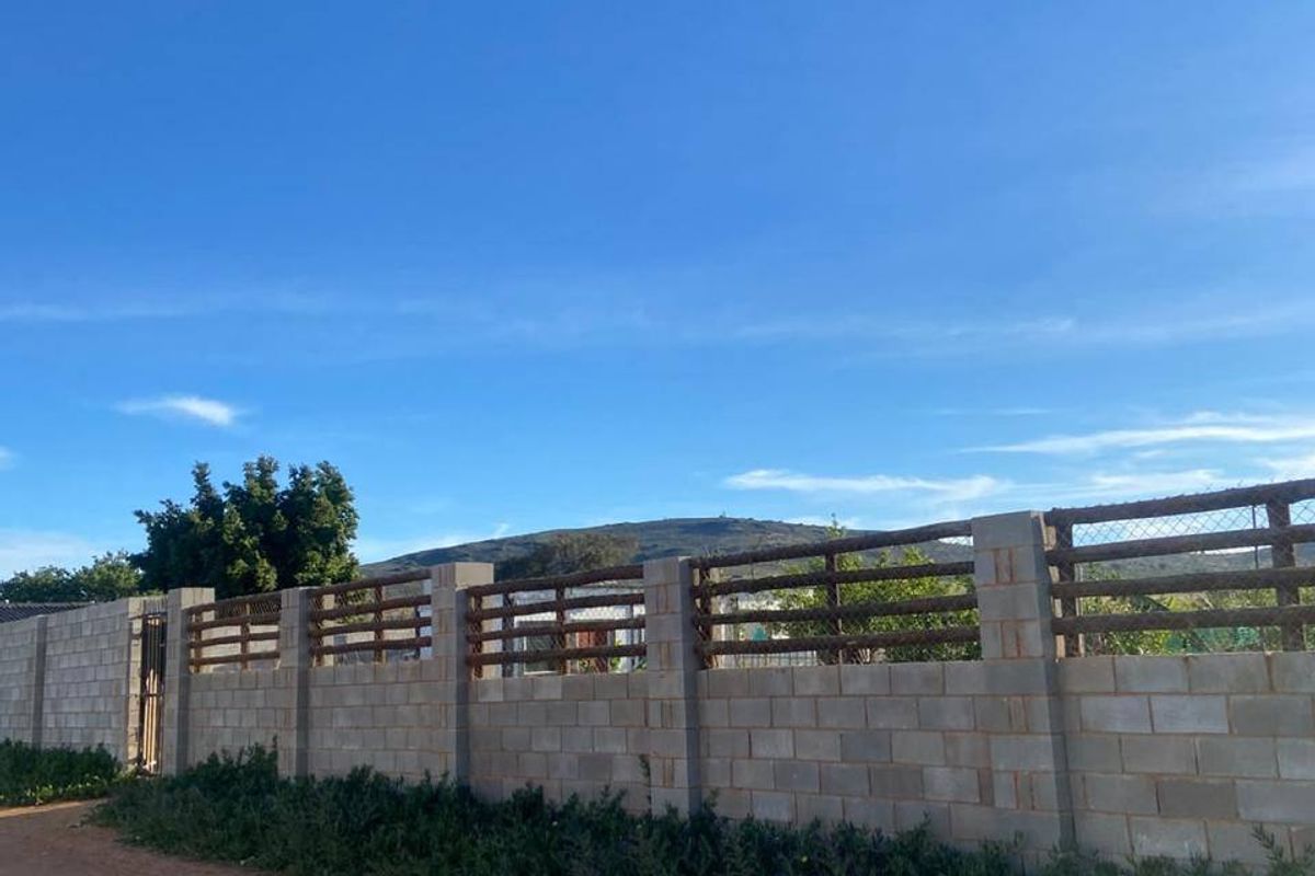 A view of the residential property boundary featuring a sturdy concrete block wall with integrated timber and wire mesh fencing.