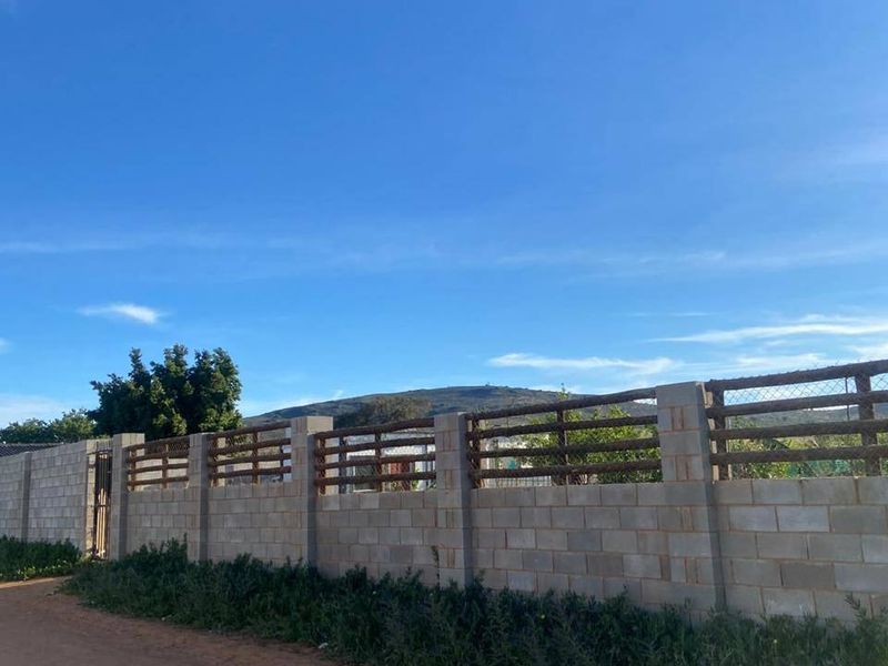 A view of the residential property boundary featuring a sturdy concrete block wall with integrated timber and wire mesh fencing.