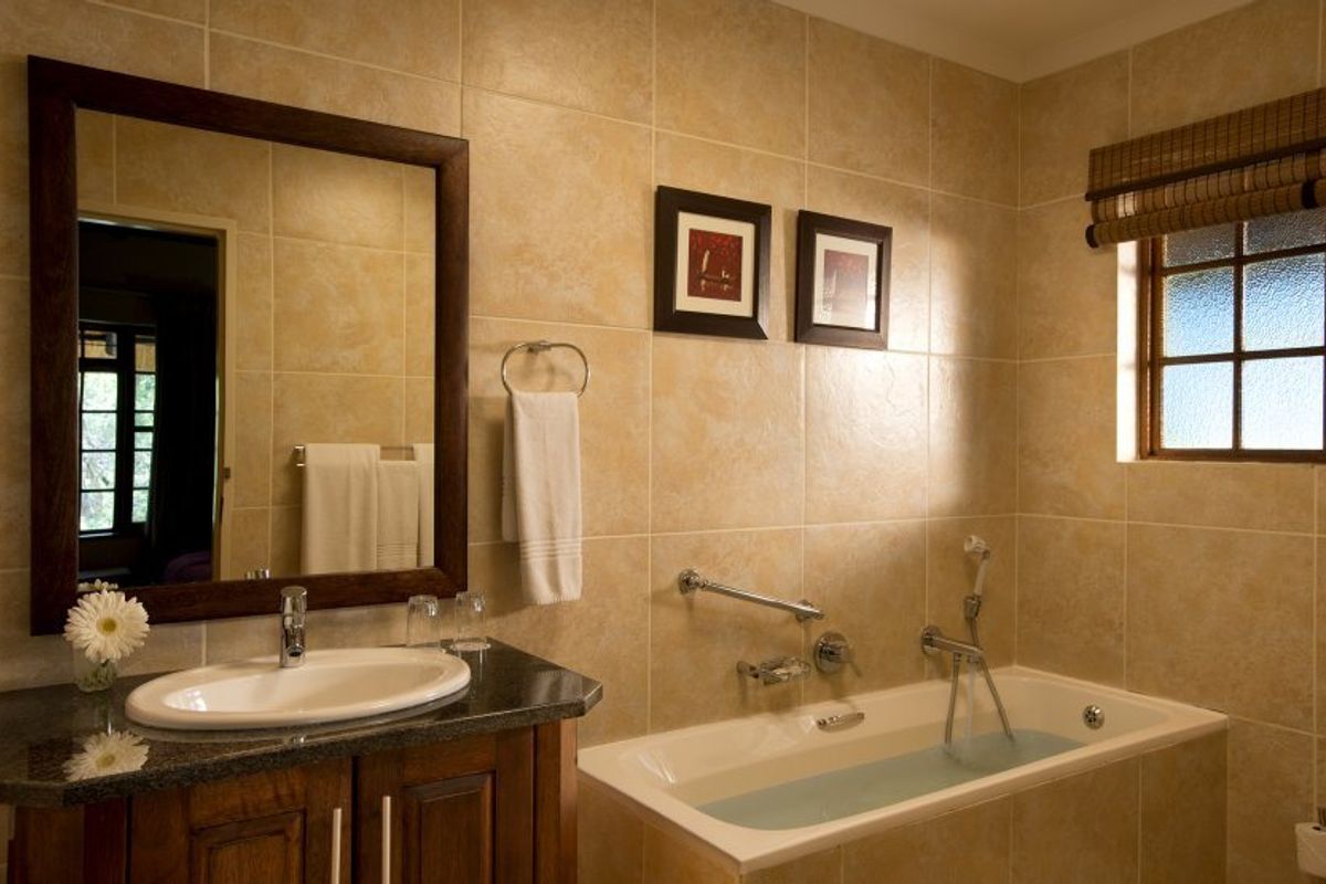 A well-maintained bathroom featuring a granite-topped vanity, tiled walls, and a built-in bathtub with integrated shower fixtures.