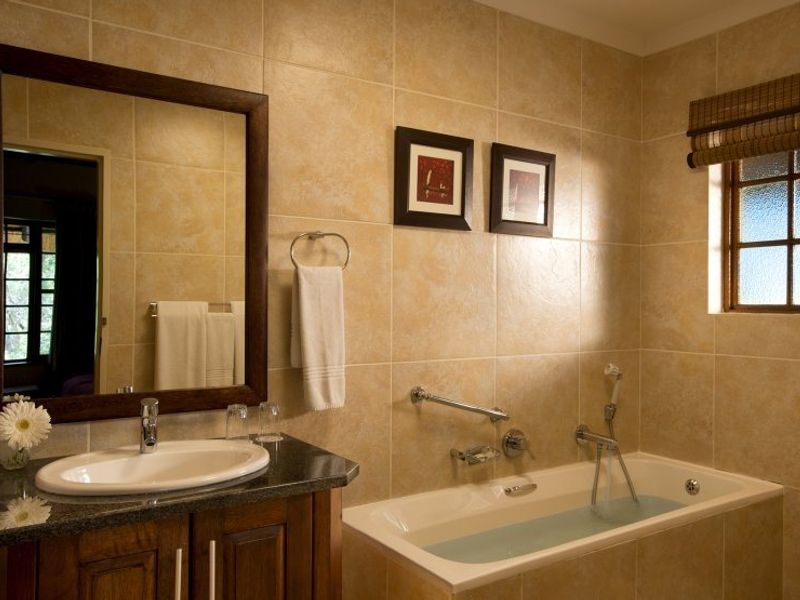 A well-maintained bathroom featuring a granite-topped vanity, tiled walls, and a built-in bathtub with integrated shower fixtures.