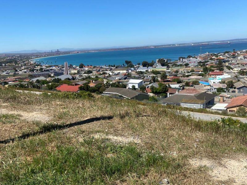 An elevated view overlooking the coastal town and bay, showcasing the expansive landscape and surrounding residential area.