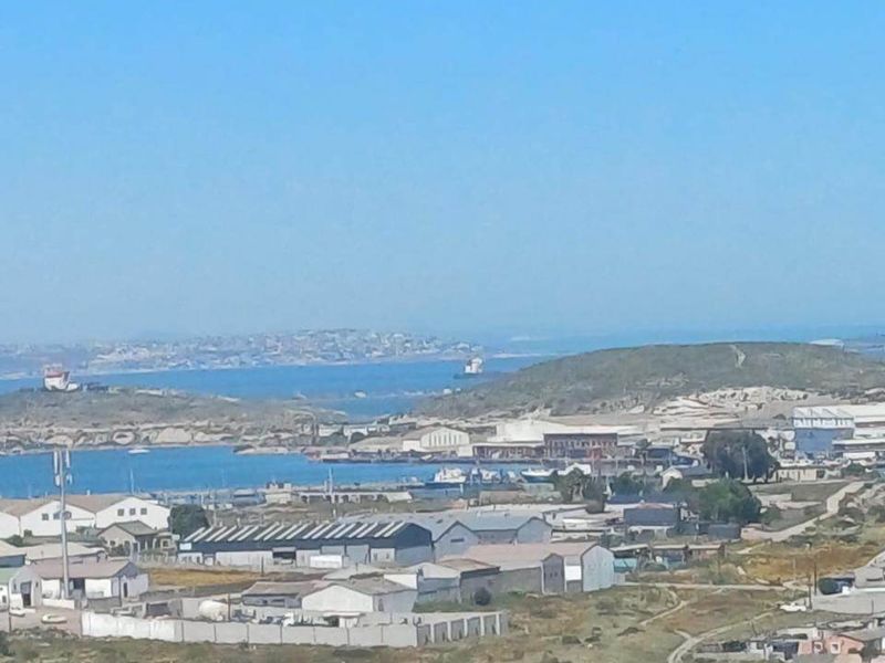 An elevated panoramic view overlooking the coastal town, industrial harbor area, and surrounding landscape.