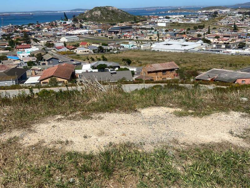 Elevated view overlooking the surrounding coastal town, residential area, and distant ocean horizon from the vacant land plot.
