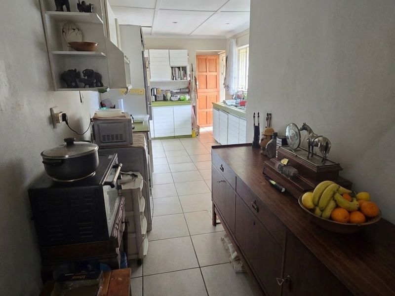 A functional kitchen area featuring tiled flooring and built-in cabinetry, offering a practical layout with potential for modernization and aesthetic updates.