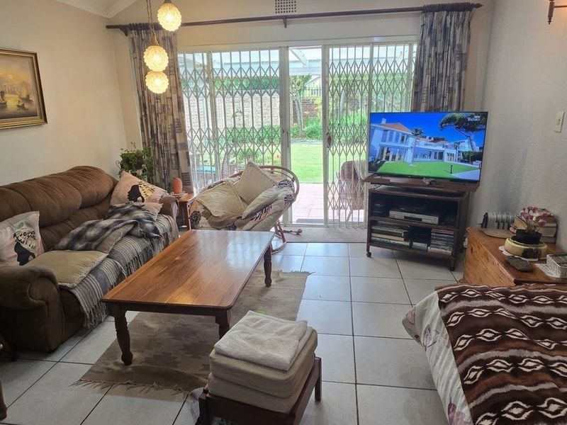 A comfortable living room featuring tiled flooring and large sliding glass doors that provide direct access to the rear garden area.