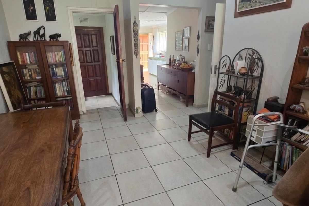 A living area featuring tiled flooring and an open archway leading to a secondary room, providing a functional and connected layout.