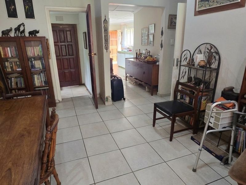 A living area featuring tiled flooring and an open archway leading to a secondary room, providing a functional and connected layout.
