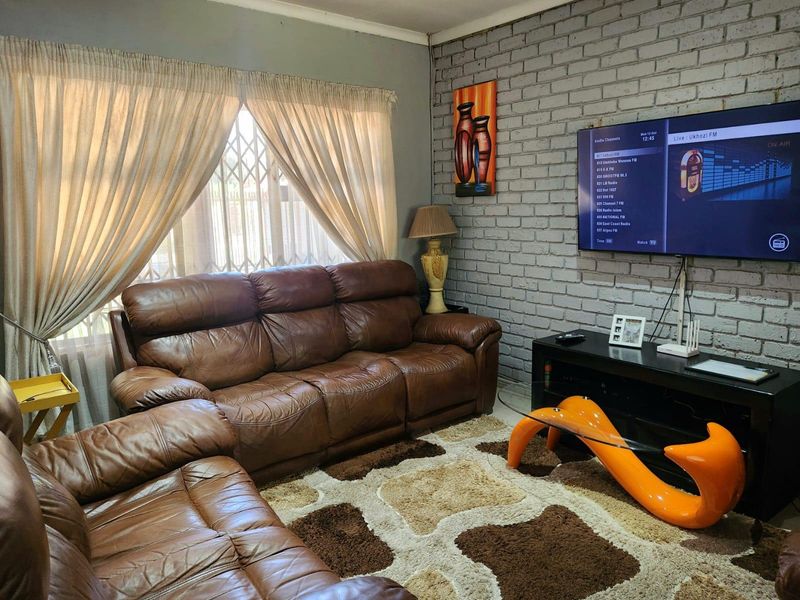 A cozy living room featuring an exposed brick feature wall and large windows with security gates, providing a comfortable and functional living space.