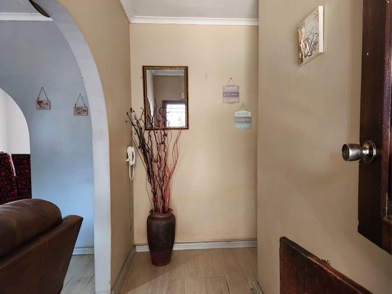 An entry hallway featuring an arched doorway, laminate flooring, and neutral wall finishes, providing a functional transition space within the home.