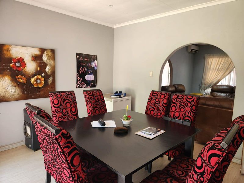 A dining room featuring a coved ceiling and a wide arched opening leading into an adjacent living space with air conditioning.