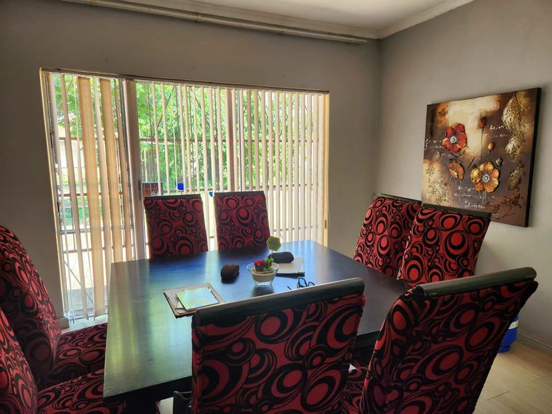 A dining room featuring laminate flooring and a large sliding glass door with vertical blinds, providing natural light and access to the exterior.
