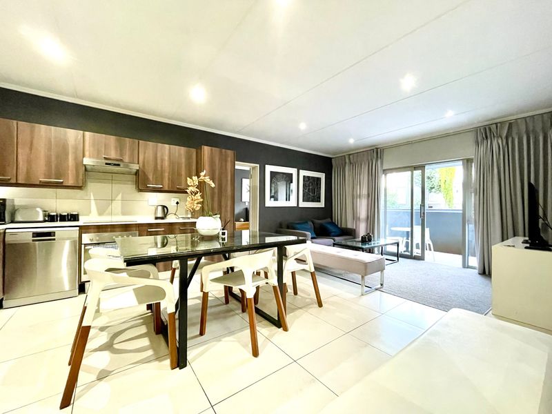 Modern open-plan living area featuring a well-appointed kitchen with built-in cabinetry and appliances, flowing seamlessly to a bright lounge with sliding door access.